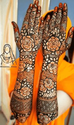 a woman is holding her hands up with henna tattoos on their arms and hand