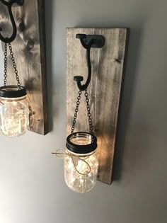 two mason jars are hanging on the wall next to a light fixture that is made out of wood