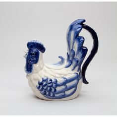 a blue and white ceramic rooster figurine on a white background with the tail curled up