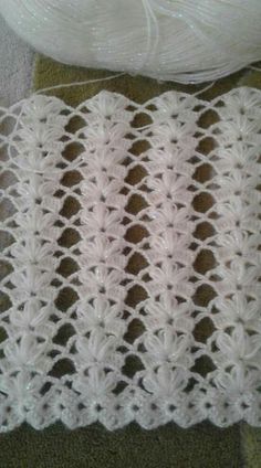 a close up of a white crochet doily on the floor next to a ball of yarn