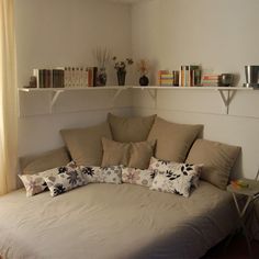 a living room with a couch, bookshelf and shelves on the wall above it