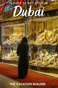 a woman standing in front of a display case filled with gold jewelry