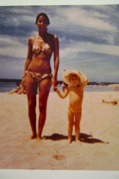 an old photo of a woman and child on the beach