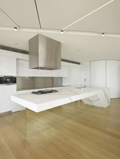 a kitchen with an island in the middle and stainless steel appliances on the back wall