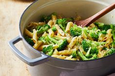 a pot filled with pasta and broccoli on top of a wooden table