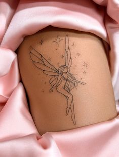 a small tattoo on the side of a woman's thigh shows a fairy holding a wand