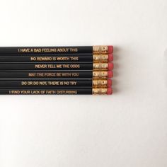 four pencils with writing on them sitting next to each other, one is black and the other is red