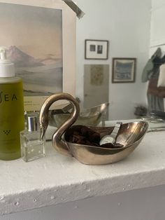 a bathroom sink with soap and lotion in it next to a painting on the wall