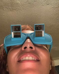 a woman with glasses on her eyes looking up at the sky while wearing a pair of blue goggles