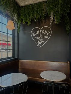 some tables and chairs are in front of a wall with writing on it that says someone praying for you