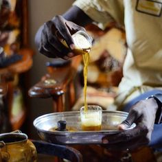 a person pouring something into a glass on top of a tray in front of a chair