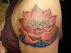 a woman with a tattoo on her shoulder has a large pink flower in the center