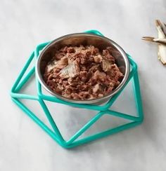 a metal bowl filled with food sitting on top of a white counter next to garlic