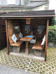 an outdoor table and bench in a wooden structure with blue cushions on it's sides