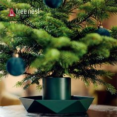 a christmas tree with ornaments hanging from it's branches and in a bowl shaped like an ornament