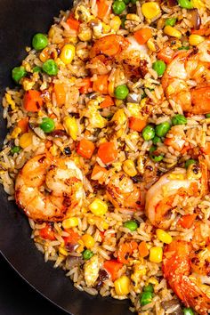 a skillet filled with shrimp, rice and peas