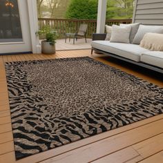 a living room area with couches and rugs on the wooden flooring outside