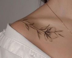 a woman's shoulder with a leaf tattoo on her left shoulder and the back of her neck