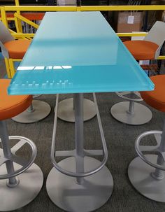 a blue table with four stools around it in a room filled with orange chairs