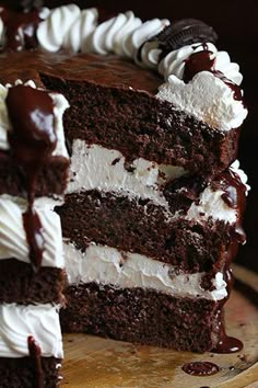 a chocolate cake with white frosting and oreo cookies on top is cut in half