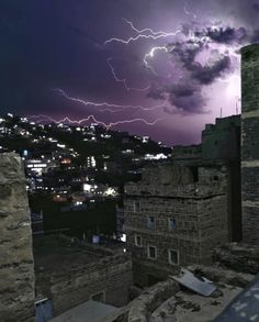 a lightning storm is seen over the city in this photo taken from an old building