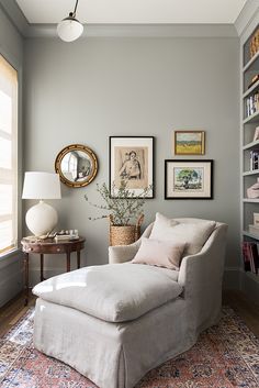 a living room with a chair, ottoman and bookshelf on the wall next to a window