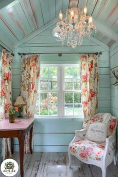 a room with a chair, table and chandelier hanging from it's ceiling