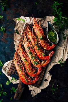 grilled lobsters on a grill with dipping sauce and parsley sprigs