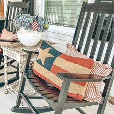 an american flag pillow sits on a rocking chair next to a small table with a potted plant