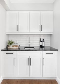 a kitchen with white cabinets and black counter tops