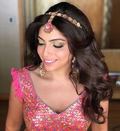 a woman with long hair wearing a head piece and earrings on her head, smiling at the camera