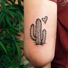 a small cactus with a heart tattoo on the left side of the arm, next to a green plant