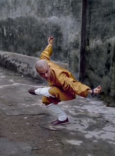 a man in an orange jacket is doing a trick on the street with his feet