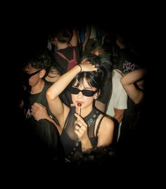 a group of people standing around each other in the dark with one woman holding a lollipop