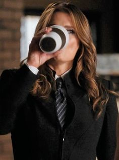 a woman in a suit drinking from a coffee cup