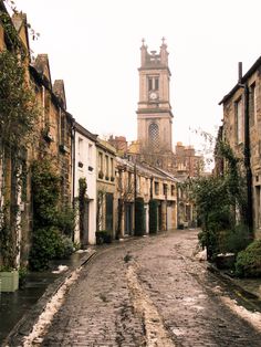 an old cobblestone street with buildings and a clock tower in the background