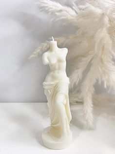 a white statue is next to a feather tree