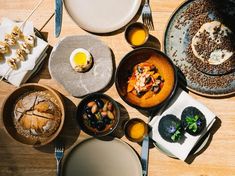 an overhead view of various dishes on a wooden table with utensils and plates