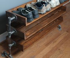 several pairs of shoes are sitting on a wooden shoe rack in front of a wall