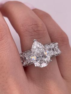 a woman's hand with two diamond rings on her left and the other hand holding an engagement ring