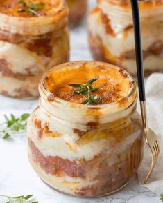 three jars filled with food sitting on top of a white table next to utensils