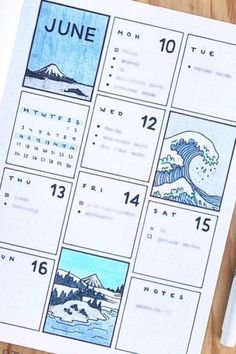 a calendar with images of waves and mountains in blue ink on a wooden table top