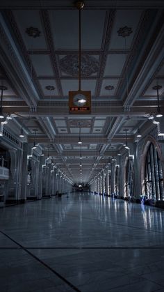 an empty room with high ceilings and lights on the ceiling is lit by two lamps