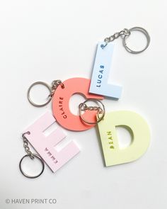 three key chains with different colored letters on them