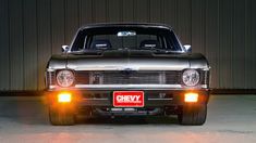 the front end of an old chevrolet car with its lights on and license plate showing