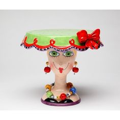 a ceramic figurine with a green hat and red bow on it's head