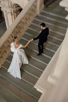 a bride and groom walking down the stairs