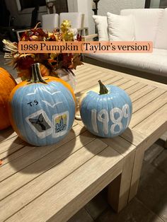 two painted pumpkins sitting on top of a wooden table next to a white couch