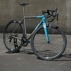 a blue and silver bike parked in front of a building with a concrete wall behind it