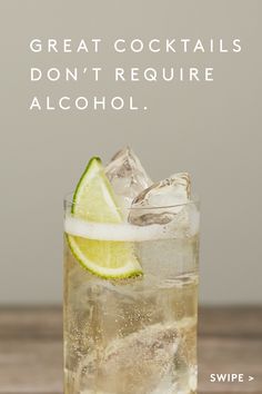 a glass filled with ice and lime on top of a wooden table